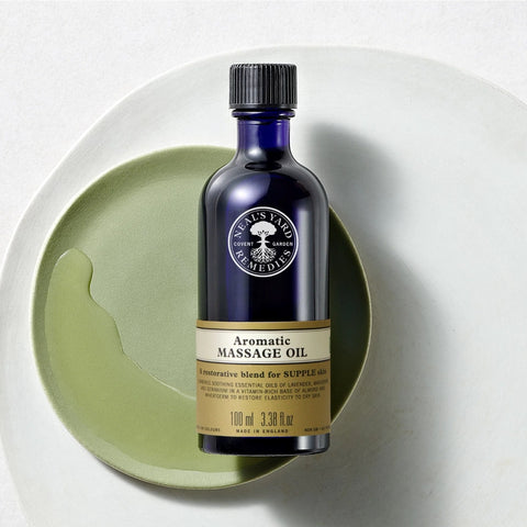 On a lovely green plate with a white linen, Neal's Yard Remedies Aromatic Massage Oil is shown. 