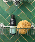Neal's Yard Remedies English Lavender Bath and Shower Gel on a shower rack with a green tile. 