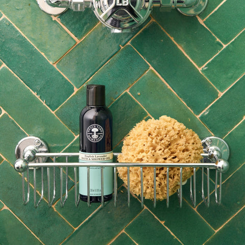 Neal's Yard Remedies English Lavender Bath and Shower Gel on a shower rack with a green tile. 