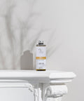 Uplifting Aromatherapy Reed Diffuser Refill bottle sitting on decorative ledge